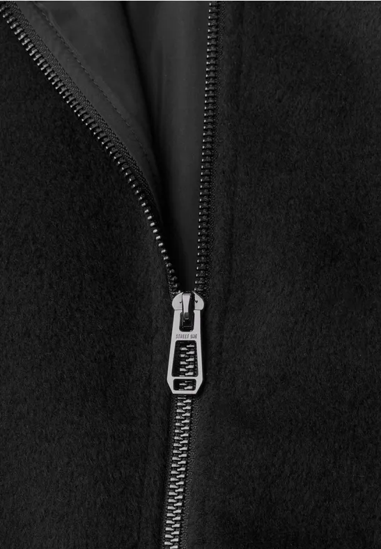 Close-up van een zilverkleurige ritssluiting op zwart fleece-stof.