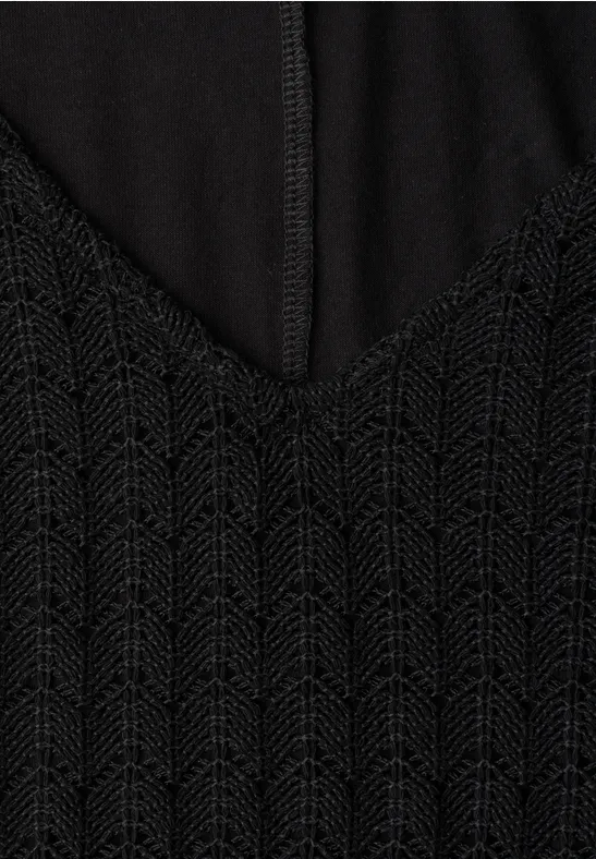 Schwarzes Oberteil mit V-Ausschnitt und fein gestricktem Zickzackmuster, Naht in der Mitte sichtbar.