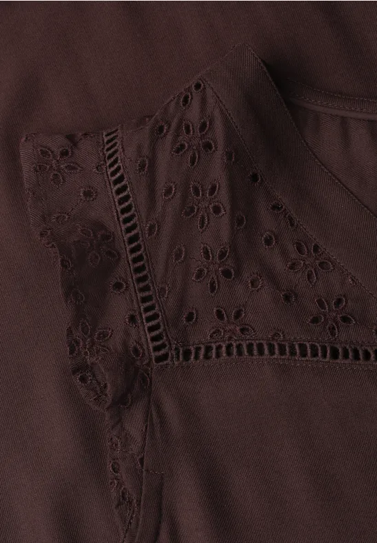 Vêtement marron orné de broderie anglaise délicate et de motifs ajourés.