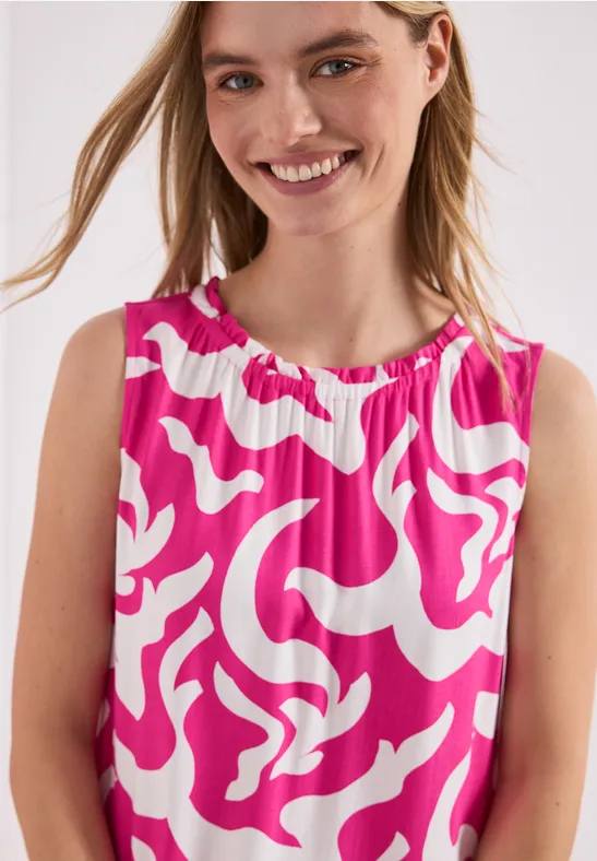 Kind trägt ärmelloses Oberteil mit pink-weißem abstraktem Muster.