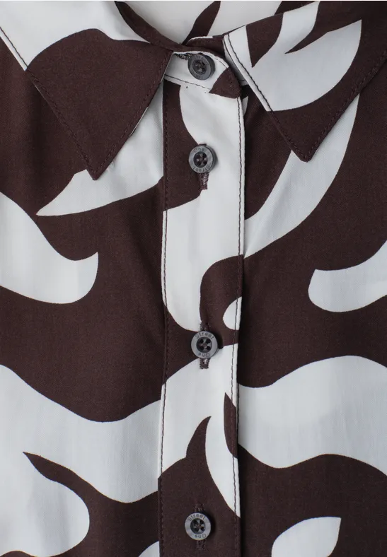 Nahaufnahme eines Hemds mit organischem schwarz-weißem Muster und schwarzen Knöpfen.