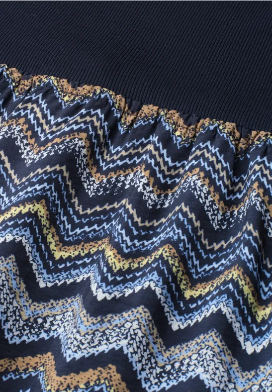 Strickstoff mit wellenförmigem Zickzackmuster in Blau, Weiß, Gelb und Braun, obere Partie dunkelblau.