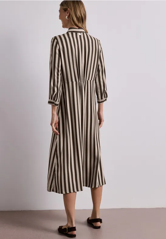 Frau von hinten in knöchellangem, gestreiftem Kleid mit schwarzen Sandalen.