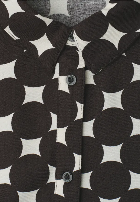 Hemd mit schwarz-weißen geometrischen Kreisen und Sternen, mit Kragen und Knöpfen.