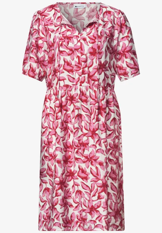 Robe mi-longue à manches courtes, motif floral rose et blanc, col en V et ceinture à la taille.