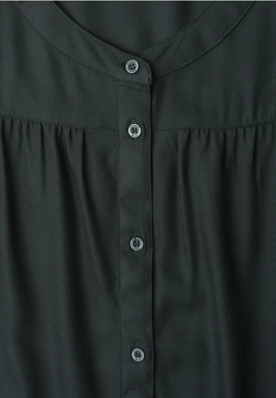 Blouse noire à encolure ronde et patte de boutonnage centrale.
