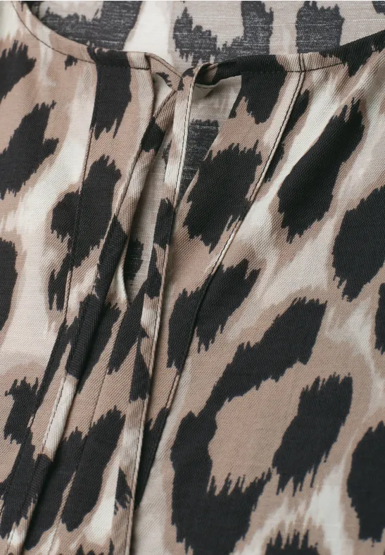 Nahaufnahme eines Bekleidungsstücks mit Leopardenmuster in Beigetönen und schwarzen Flecken.