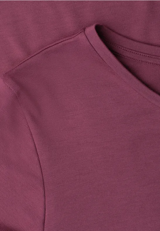 Nahaufnahme eines burgunderfarbenen T-Shirts aus weichem Stoff mit Rundhalsausschnitt.