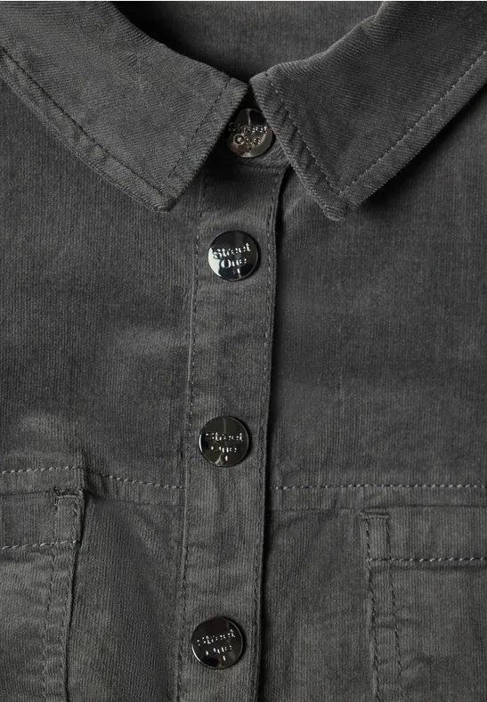 Close-up einer dunkelgrauen Cordhemdjacke mit Kragen, vier silbernen Knöpfen und aufgesetzten Taschen
