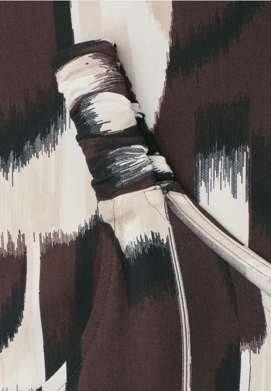 Gros plan sur un lien de tissu à motif abstrait de coups de pinceau marron et beige.
