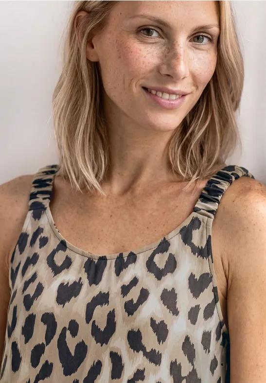 Frau im ärmellosen Tanktop mit Leopardenmuster, sichtbarer Hals- und Schulterbereich.