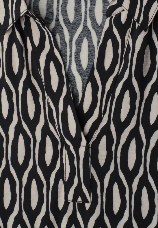 Schwarzer Stoff mit weißem, ovalem Ikat-Muster.