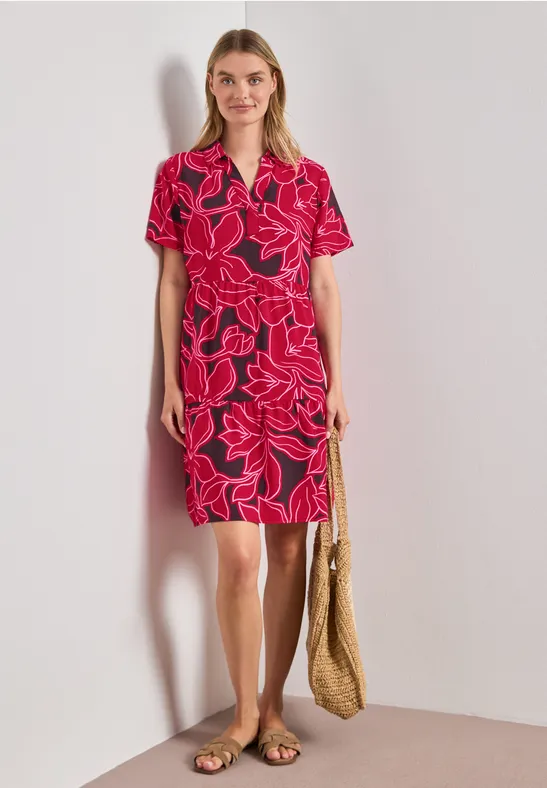Femme en robe rouge à fleurs, col V, manches courtes, sac en paille et sandales plates