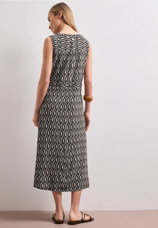 Achteraanzicht van een vrouw in een mouwloze midi-jurk met zwart-beige geometrisch patroon en tailleband