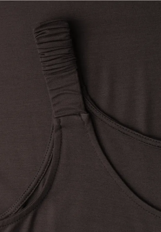 Detailaufnahme eines schwarzen Oberteils mit gerafftem Träger aus elastischem Stoff.