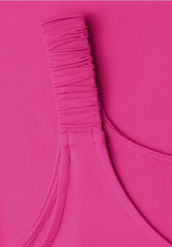 Nahaufnahme eines pinkfarbenen Kleidungsstücks mit gerafftem Träger.