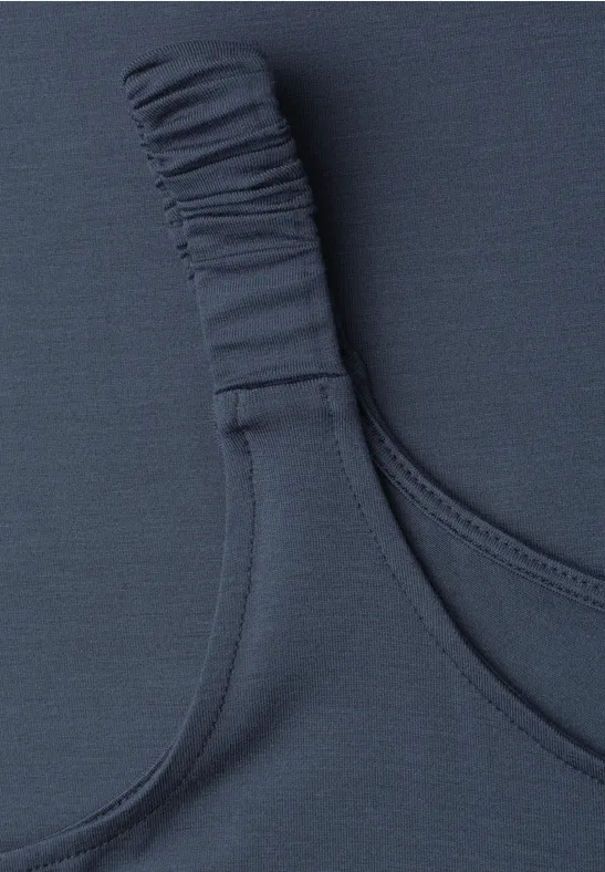 Nahe Aufnahme eines dunkelblauen BH-Trägers mit elastischem Detail auf einem Textilstoff.
