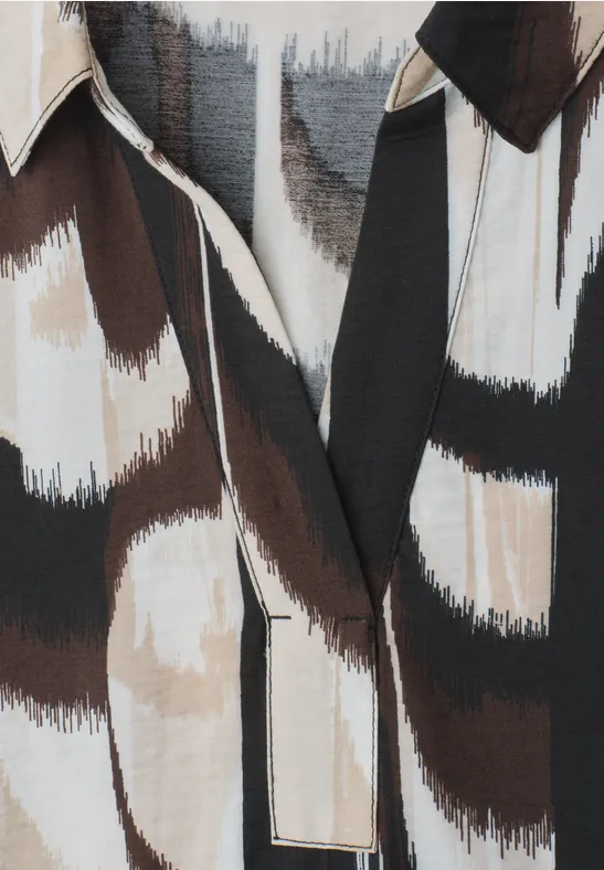 Close-up van een overhemd met abstract penseelstrekenmotief in zwart, bruin en wit.