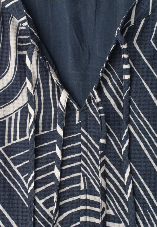 Dunkelblaues Kleid mit weißem geometrischem Streifenmuster und V-Ausschnitt.