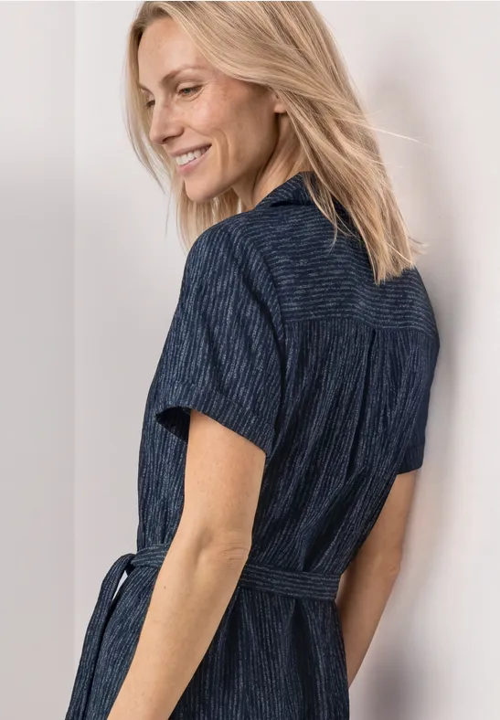 Frau mit schulterlangen, blonden Haaren trägt ein tailliertes, marineblaues Hemdkleid mit kurzem Arm.