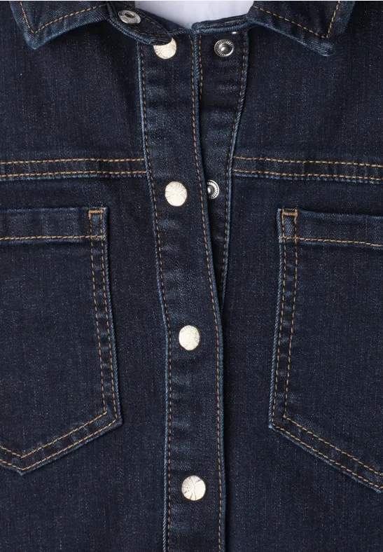 Dunkelblaue Jeansjacke mit silbernen Druckknöpfen und zwei Brusttaschen in Nahaufnahme.