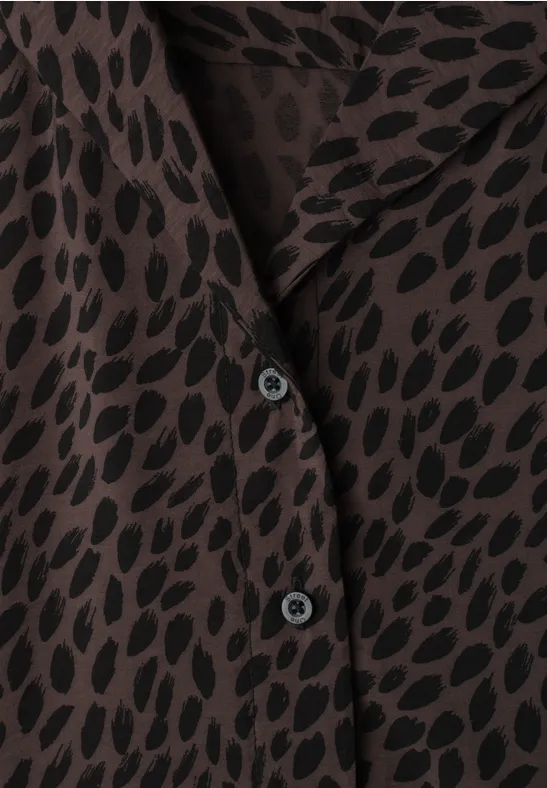 Close-up van een bruin overhemd met zwart patroon en zwarte knopen.