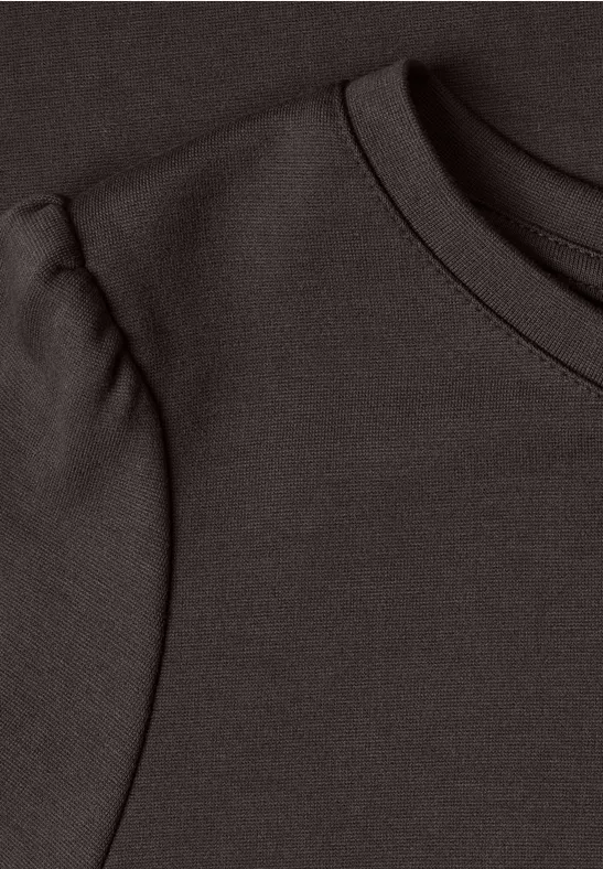 Gros plan de l'encolure d'un t-shirt marron foncé avec un détail plissé sur l'épaule.