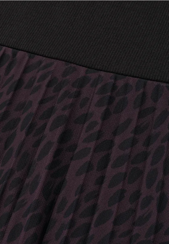 Nahaufnahme eines violetten, plissierten Rockes mit schwarzem Bund und dezentem, dunklem Muster.
