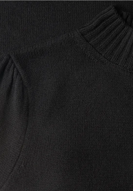 Nahaufnahme eines schwarzen Strickpullovers mit hohem Kragen.