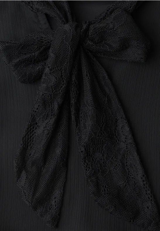 Schwarze Spitzen-Schleife an einem Kleidungsstück.