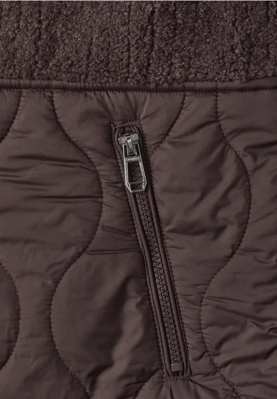Nahaufnahme einer braunen Steppjacke mit Ziersteppung und seitlichem Reißverschlussfach.