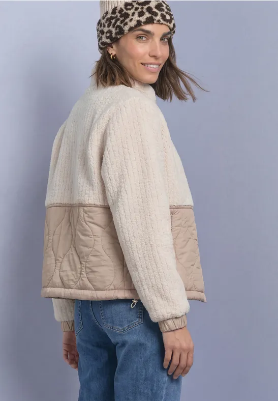 Frau trägt wattierte Jacke in Beige und Creme, kombiniert mit Leopardenmuster-Tuch und Jeans.