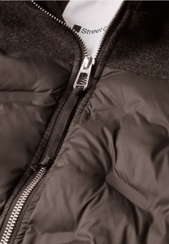 Nahaufnahme einer schwarz-grauen Steppjacke mit sichtbarem silbernen Reißverschluss.