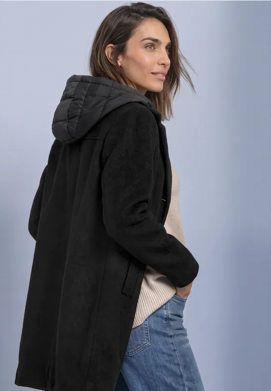 Une femme de profil porte un manteau à capuche noir.