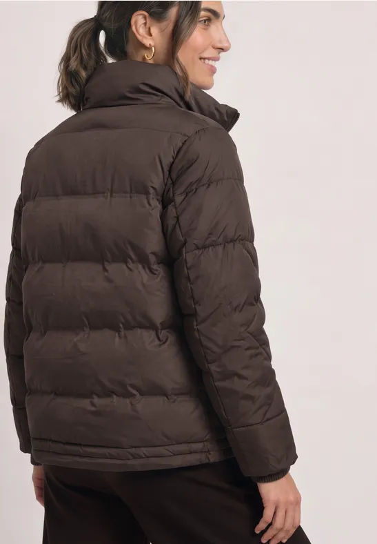 Frau in brauner Steppjacke und Hose, von hinten gesehen.