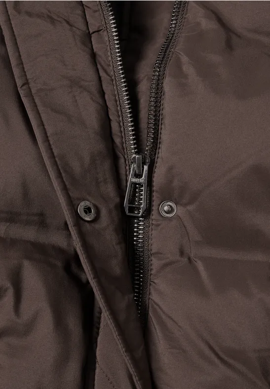Nahaufnahme eines Reißverschlusses und zweier Druckknöpfe an brauner Jacke.