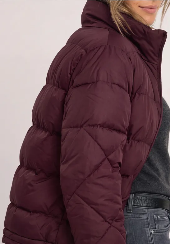 Vrouw in profiel met een bordeaux gewatteerd jack