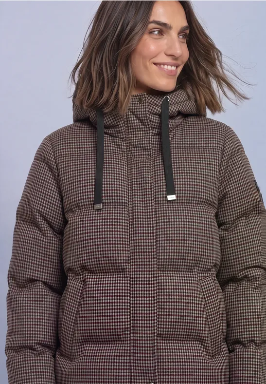 Frau in braun kariertem, wattiertem Winterparka mit Kapuze und aufgesetzten Taschen.