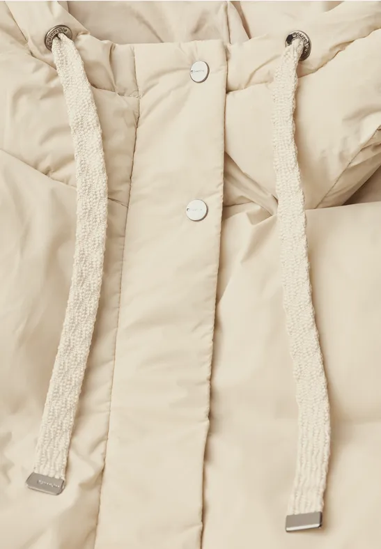 Beige doorgestikte jas met dikke koordsluiting bij de capuchon en zilverkleurige drukknopen.