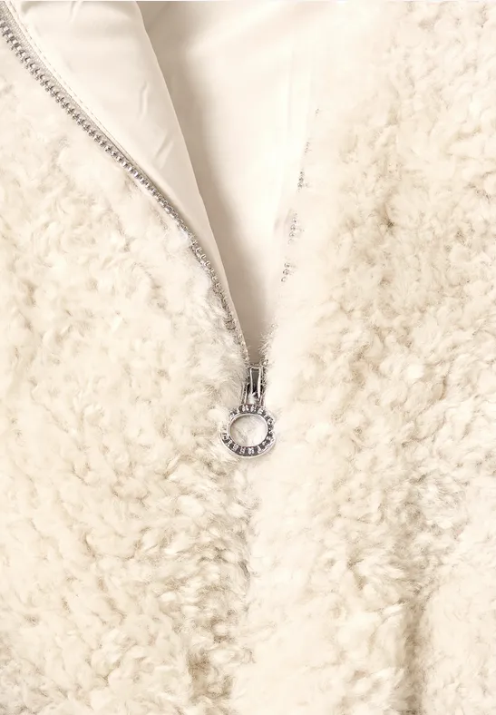 Weißer Teddy-Fleece-Reißverschluss mit silbernem Ringanhänger an weichem, flauschigem Stoff.