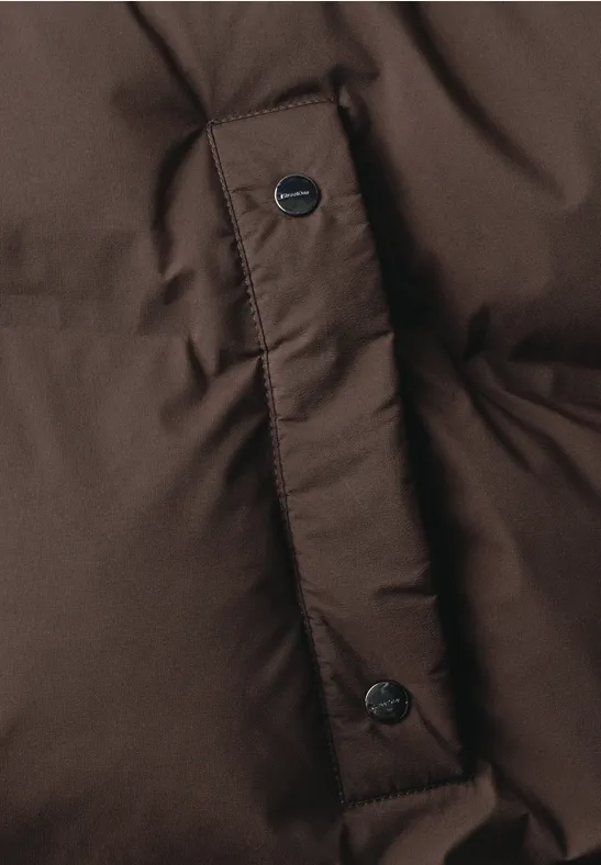 Nahaufnahme einer braunen Steppjacke mit Druckknöpfen.