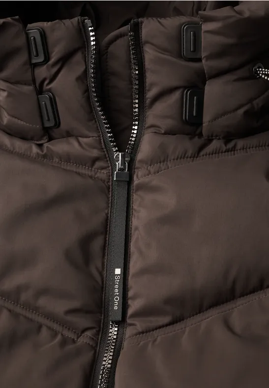 Nahaufnahme einer dunkelbraunen, gesteppten Jacke mit Reißverschluss und Zipper-Anhänger.