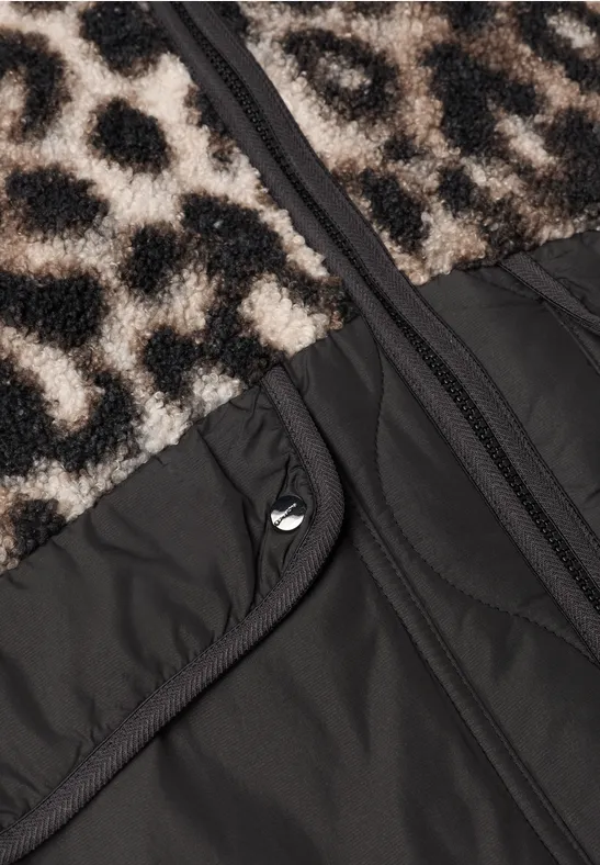 Nahaufnahme einer Jacke mit Leopardenmuster-Fellbesatz, schwarzem Gewebe, Reißverschluss und Druckknopftasche.