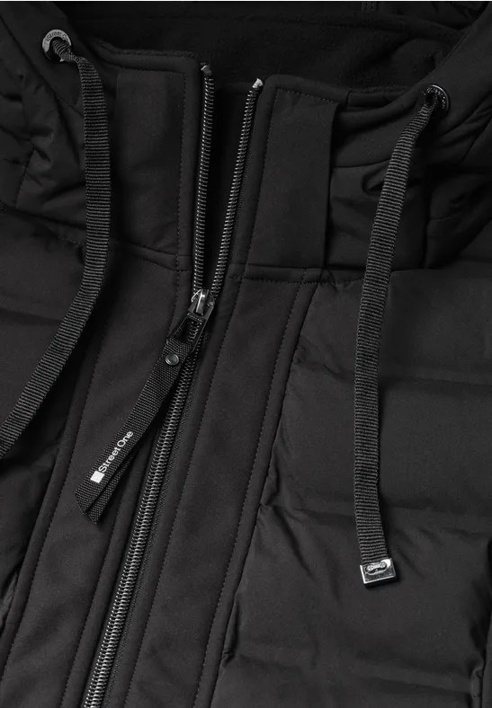 Nahaufnahme einer schwarzen Steppjacke mit Kapuze und Reißverschluss.