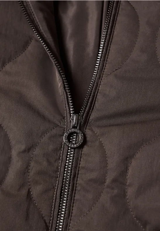 Nahaufnahme einer braunen, gesteppten Jacke mit teilweise geöffnetem Reißverschluss.