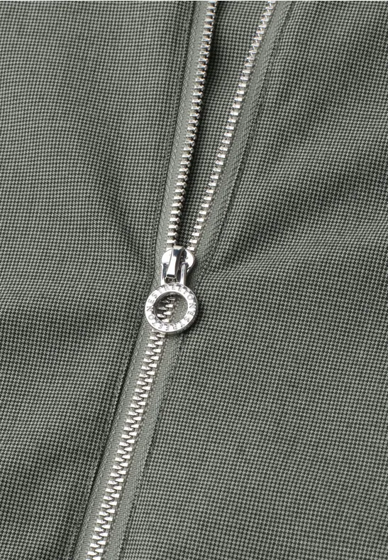 Nahaufnahme eines silbernen Reißverschlusses an olivgrünem Stoff.