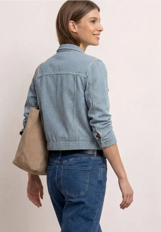 Rugaanzicht van een vrouw in jeansjack en jeans, met een tas over haar schouder.