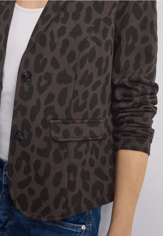 Brauner Blazer mit schwarzem Leopardenmuster über weißem Top und Jeans.