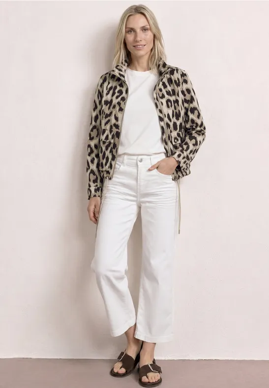Frau trägt Leopardenjacke, weißes T-Shirt, weiße Culotte-Jeans und schwarze Sandalen.