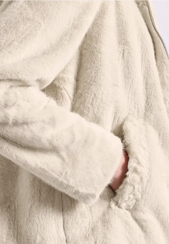 Helle, flauschige Fleecejacke aus Teddy-Stoff, Hand steckt in seitlicher Tasche.